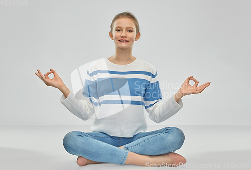 Image of smiling teenage girl meditating in lotus pose