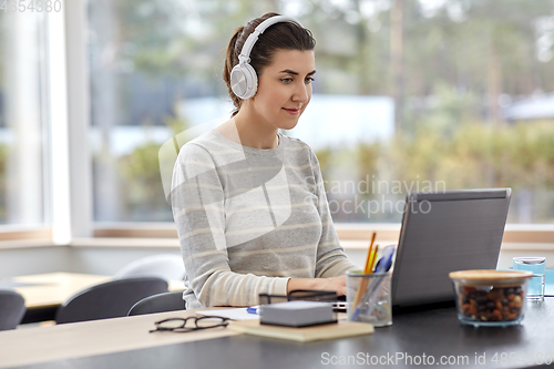 Image of woman in headphones with laptop working at home