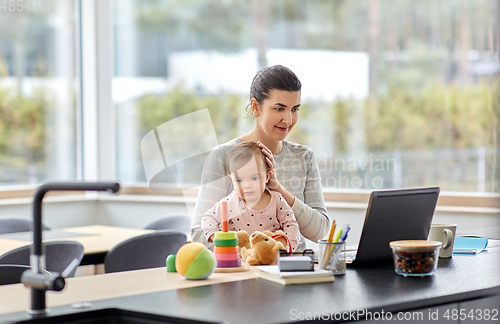 Image of mother with baby and laptop working at home office