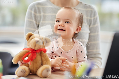 Image of happy baby with mother working at home office