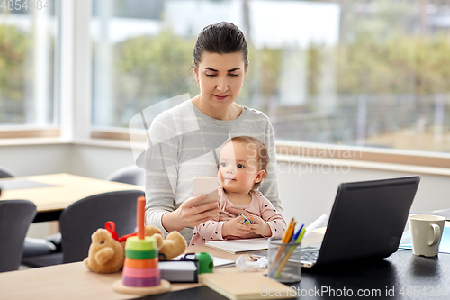Image of mother with baby and phone working at home office