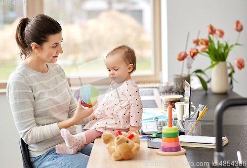 Image of happy mother with baby working at home office