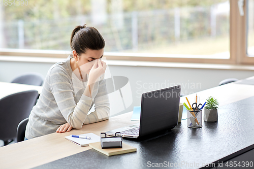 Image of tired woman with laptop working at home office