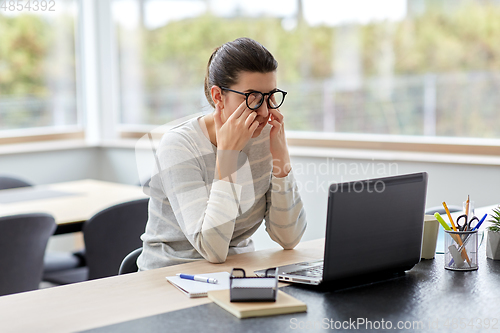 Image of tired woman with laptop working at home office