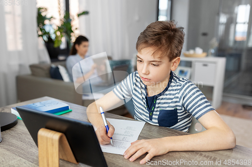 Image of student boy with tablet computer learning at home