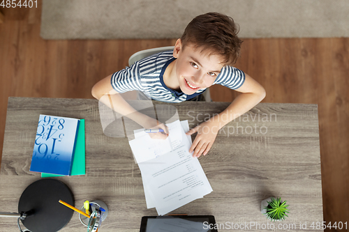 Image of happy student boy writing test at home