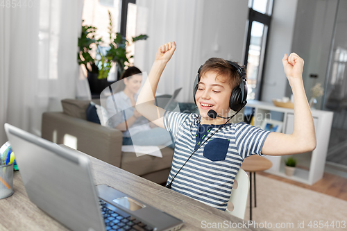 Image of boy with laptop and headphones at home