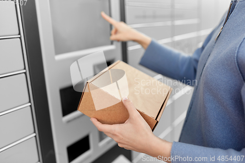 Image of smiling woman with box at automated parcel machine