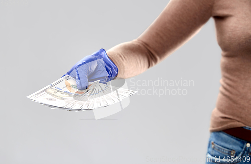 Image of close up of hand in medical glove with money