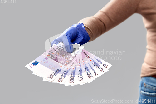 Image of close up of hand in medical glove with money