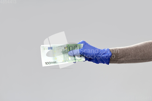 Image of close up of hand in medical glove with money