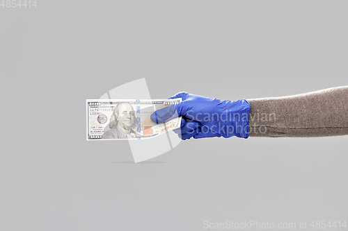 Image of close up of hand in medical glove with money