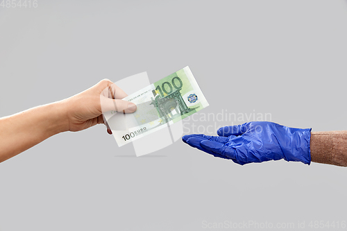 Image of close up of hand in medical glove giving money