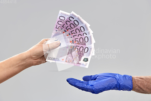 Image of close up of hand in medical glove giving money