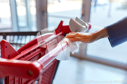 Image of hand cleaning shopping cart handle with wet wipe