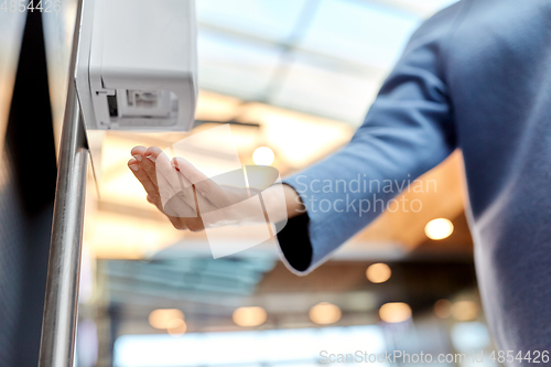 Image of close up of woman at dispenser with hand sanitizer