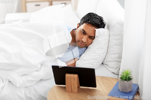 Image of happy indian man with tablet pc in bed at home