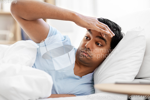 Image of indian man lying in bed at home