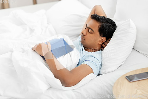 Image of indian man with book sleeping in bed at home