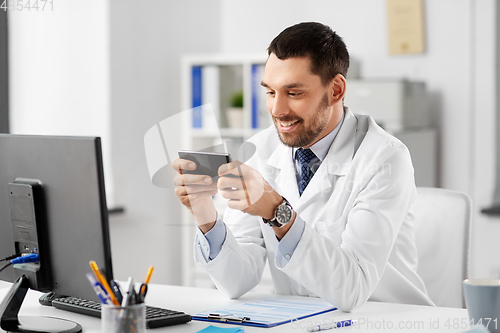 Image of smiling male doctor with smartphone at hospital