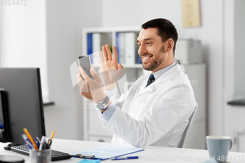 Image of doctor with smartphone having video call at clinic