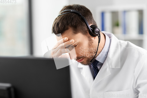 Image of male doctor with computer and headset at hospital