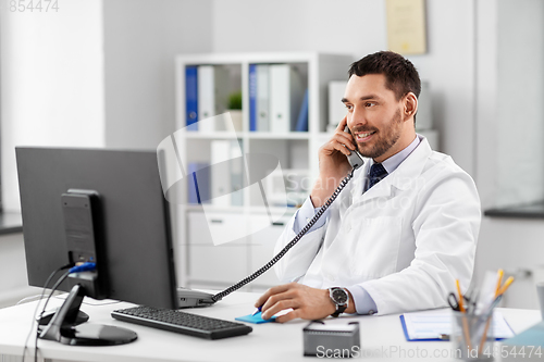 Image of male doctor calling on desk phone at hospital