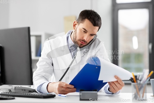 Image of male doctor calling on desk phone at hospital