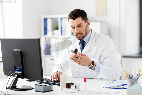 Image of male doctor with medicine and computer at hospital