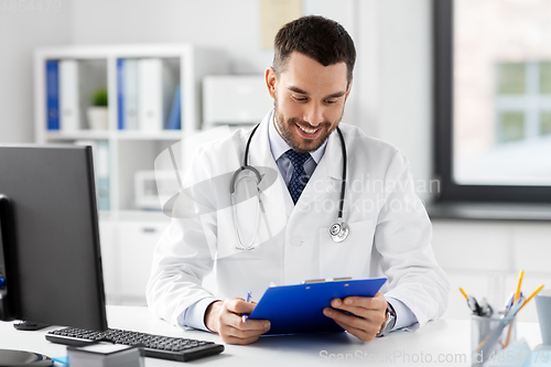 Image of smiling male doctor with clipboard at hospital