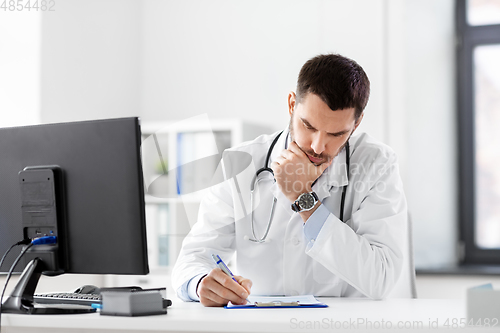 Image of stressed male doctor with clipboard at hospital