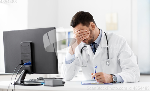 Image of stressed male doctor with clipboard at hospital