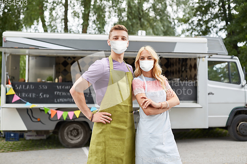 Image of couple of young sellers in masks at food truck