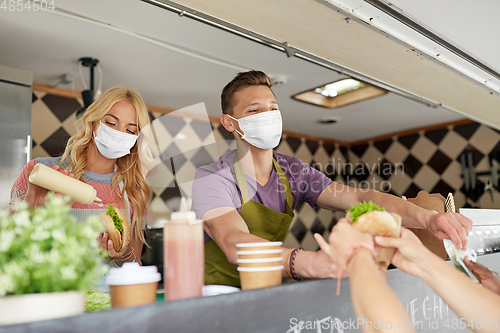 Image of sellers in masks serving customers at food truck