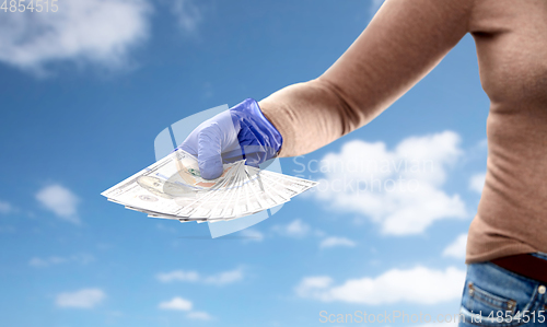 Image of close up of hand in medical glove with money