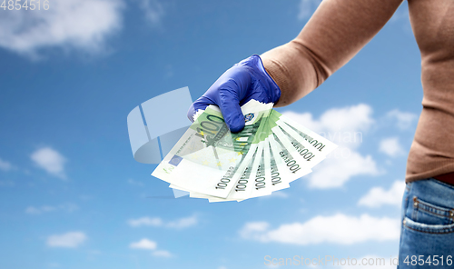 Image of close up of hand in medical glove with money