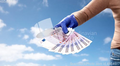 Image of close up of hand in medical glove with money