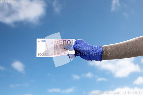 Image of close up of hand in medical glove with money