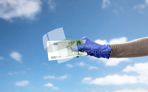 Image of close up of hand in medical glove with money