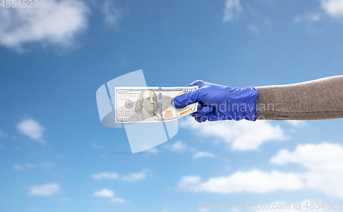 Image of close up of hand in medical glove with money