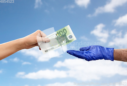 Image of close up of hand in medical glove giving money