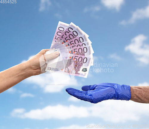 Image of close up of hand in medical glove giving money