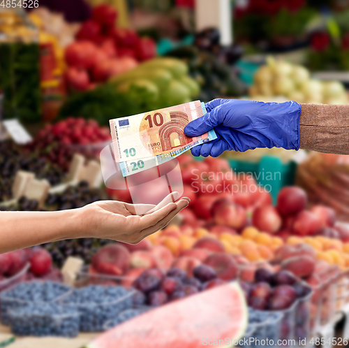 Image of close up of hand in medical glove giving money