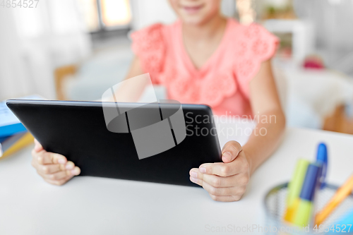 Image of little student girl using tablet computer at home