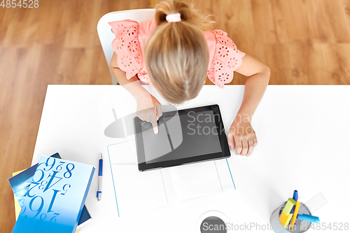 Image of little student girl using tablet computer at home