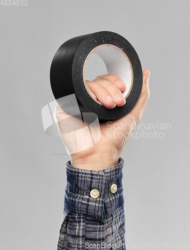 Image of close up of builder's hand holding adhesive tape