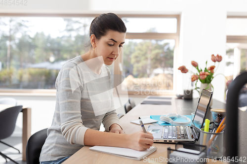 Image of young woman with laptop working at home office