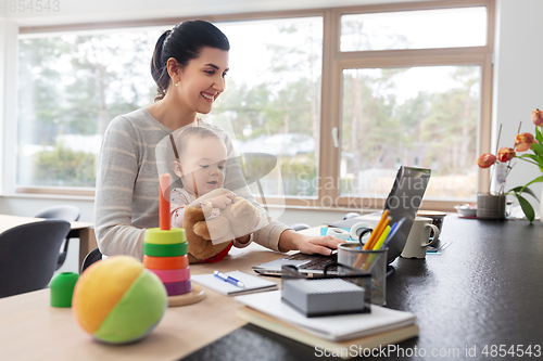 Image of mother with baby and laptop working at home office