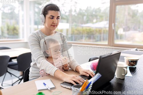 Image of mother with baby working on laptop at home office