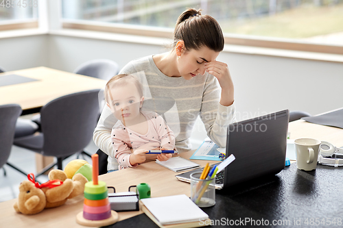 Image of tired mother with baby working at home office